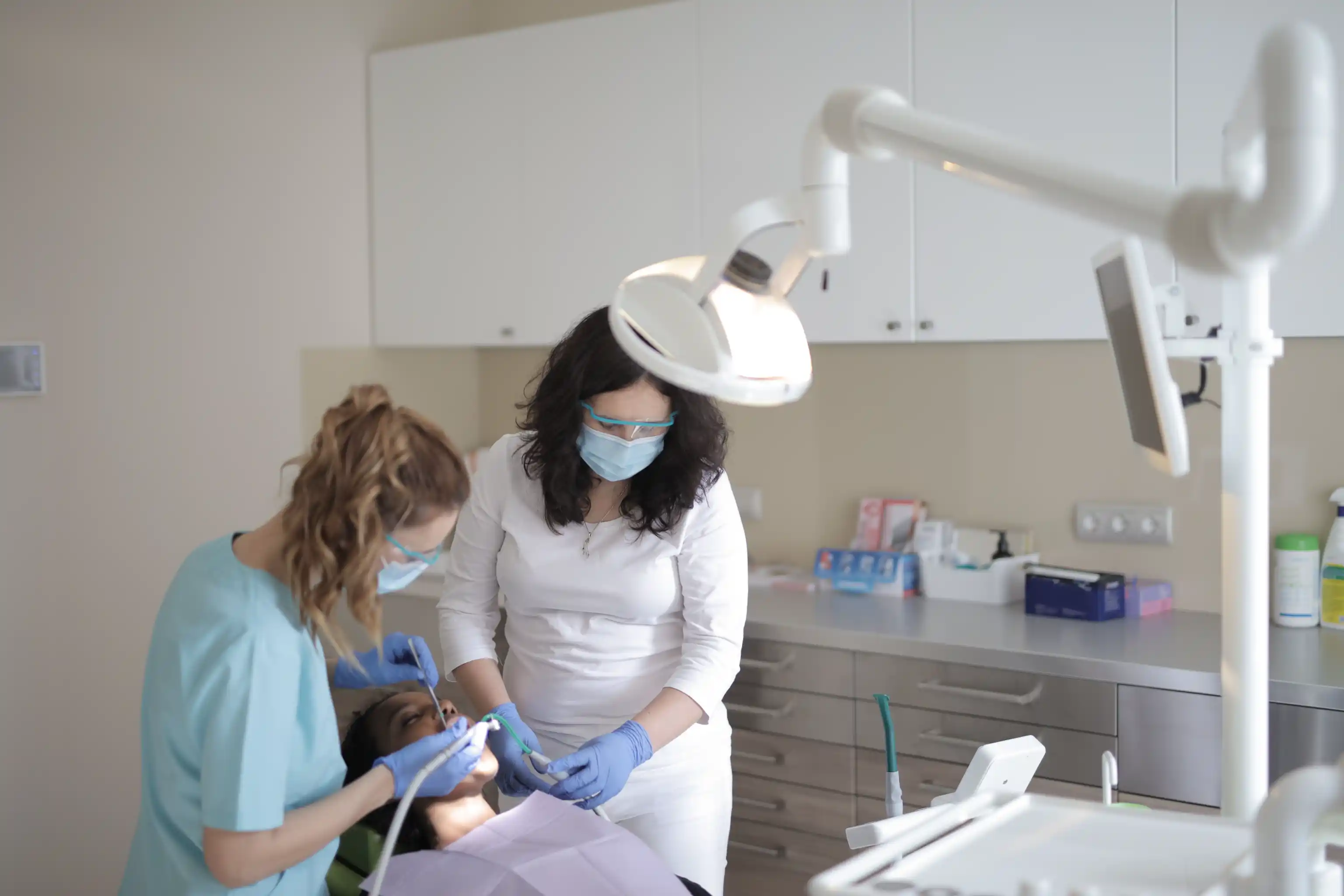 A dentist and assistant in masks caring for a patient in a dental chair