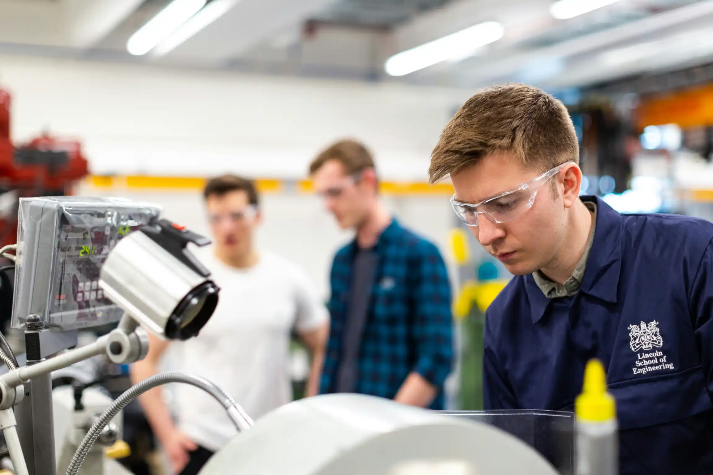 Three engineers talking beside industrial equipment on a plant floor