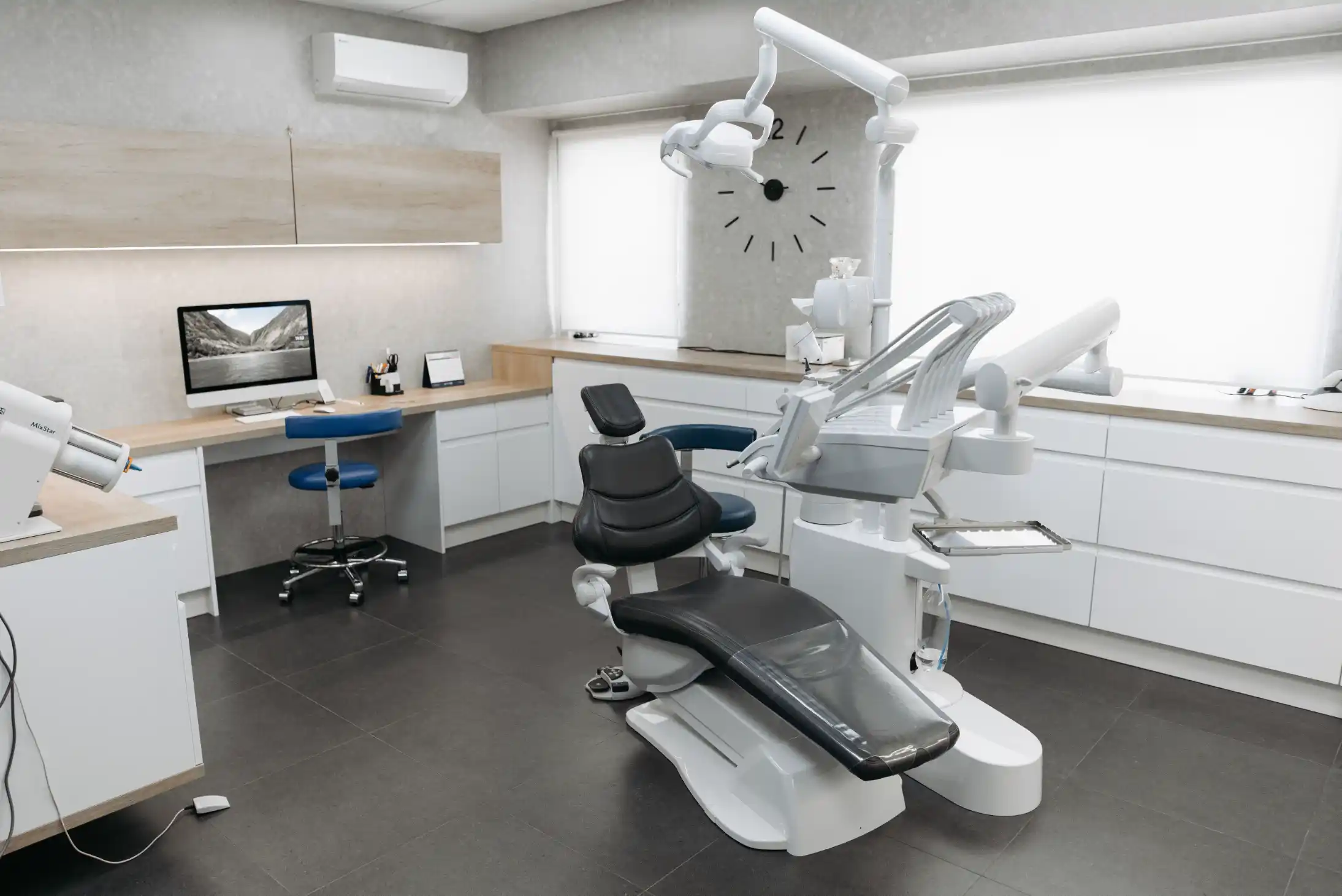 An empty, modern dental treatment room with the chair and overhead light