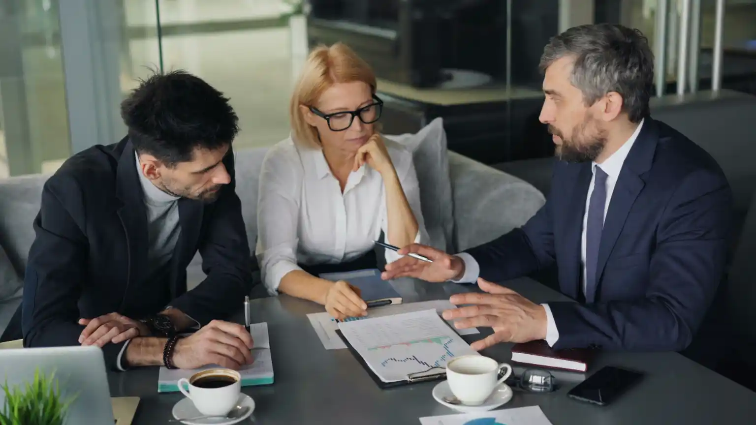 Three colleagues reviewing a printed report together at a meeting table
