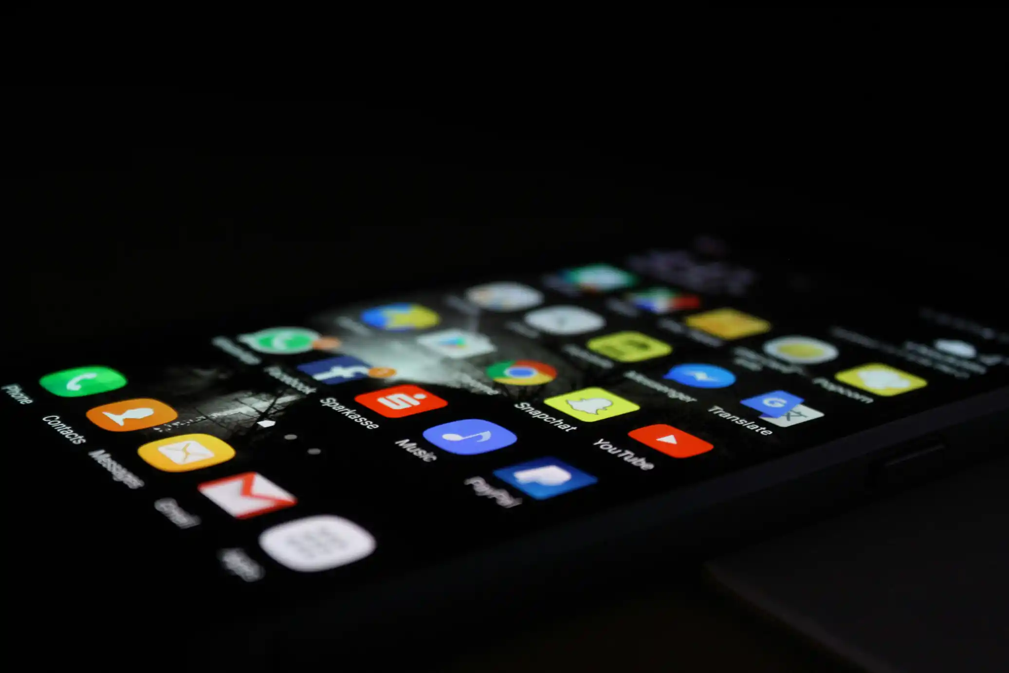 A smartphone on a dark surface showing a screen of app icons