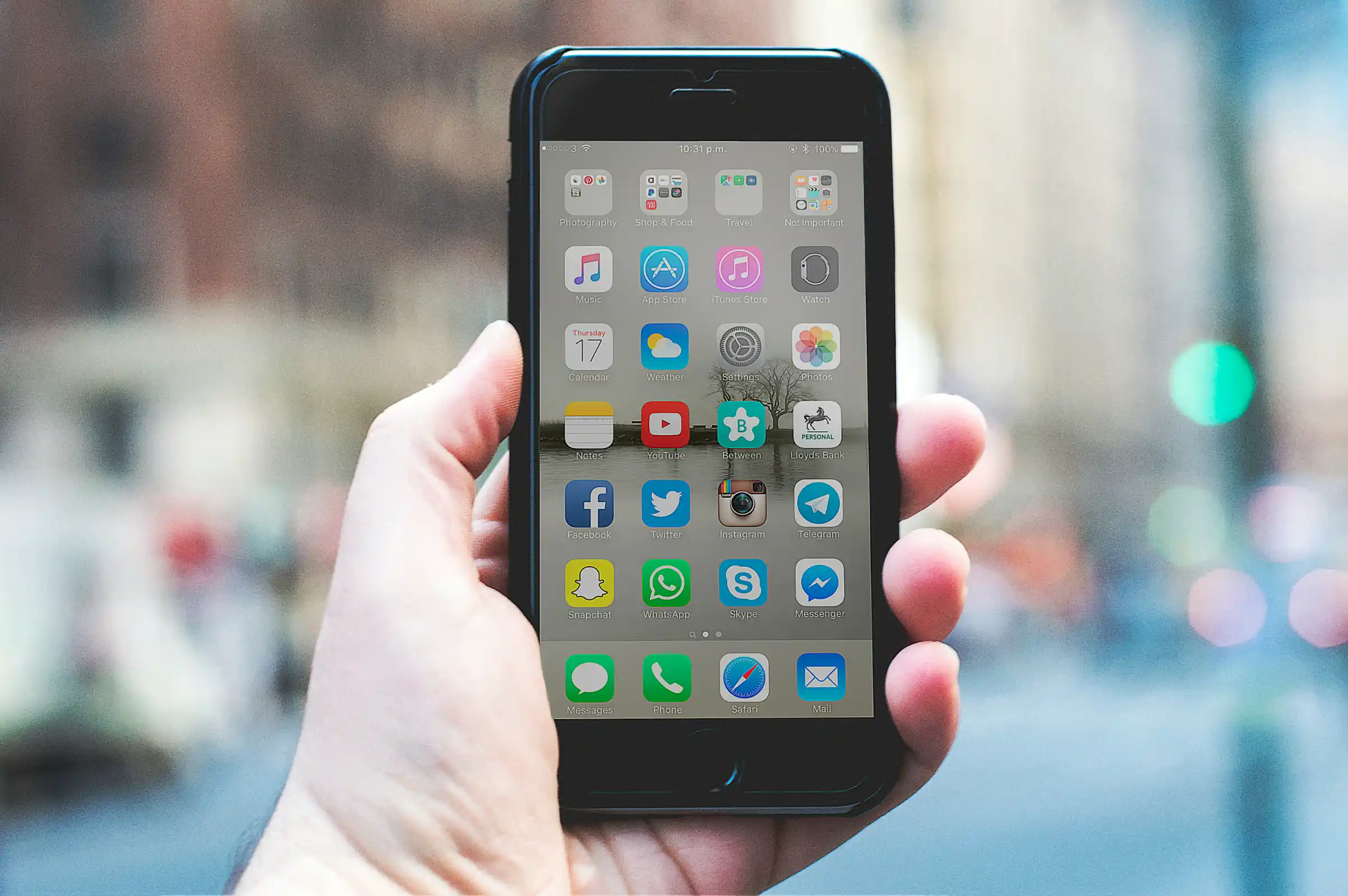 A hand holding a smartphone on a busy city street